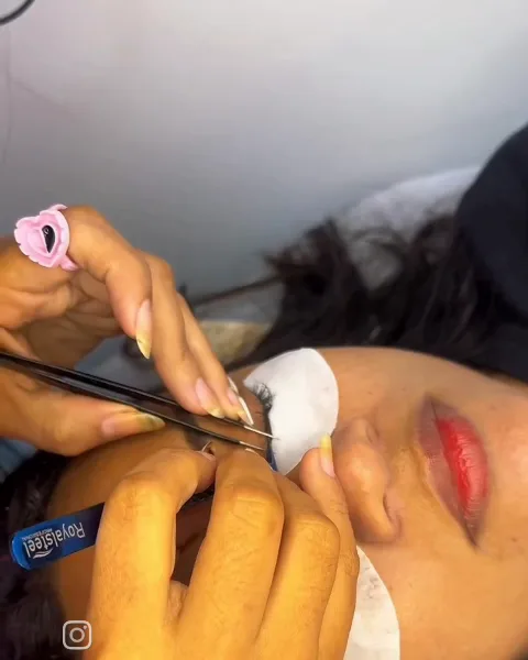 Profissional aplicando extensão de cílios com pinça, fio a fio